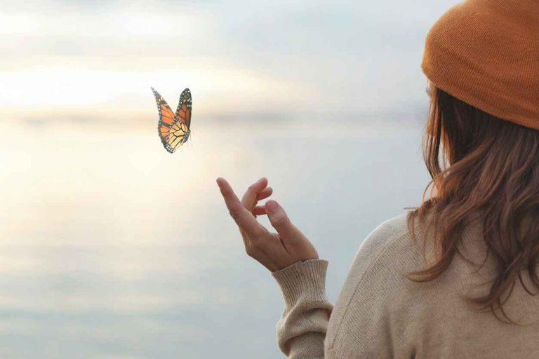 Woman holding out her finger to release a butterfly symbolizing transformation.